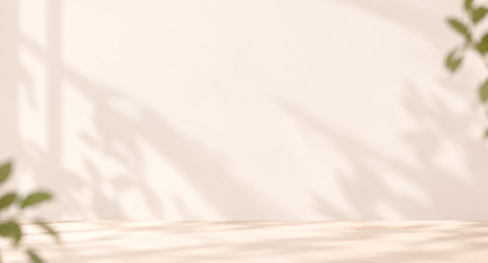 A sunlit studio backdrop with soft leaf shadows on a wall above a wooden table